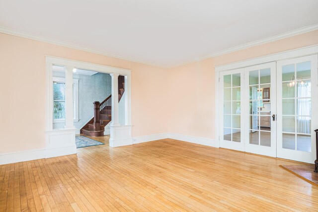 493 Main St, Eliot, ME 03903 - spare room featuring light wood-type flooring, ornate columns, ornamental molding, stairway, and baseboards