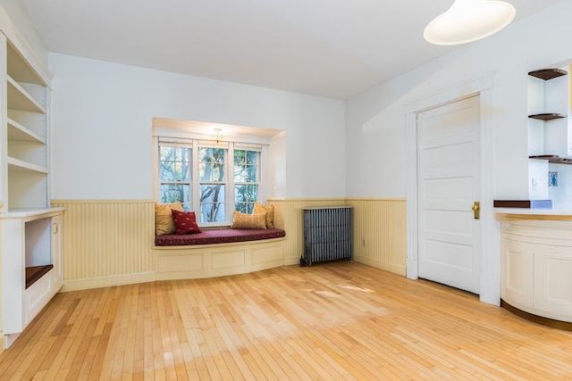 493 Main St, Eliot, ME 03903 - empty room with light wood-style flooring, wainscoting, radiator heating unit, and a fireplace