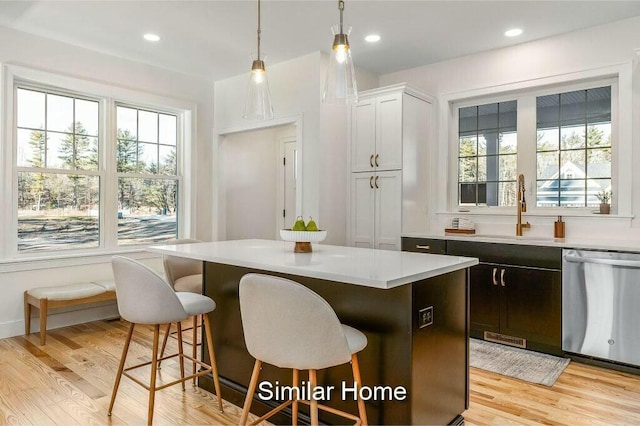 kitchen with a kitchen breakfast bar, stainless steel dishwasher, a healthy amount of sunlight, and light countertops