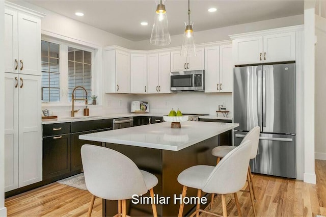 kitchen featuring a breakfast bar, light wood-style floors, appliances with stainless steel finishes, and a sink