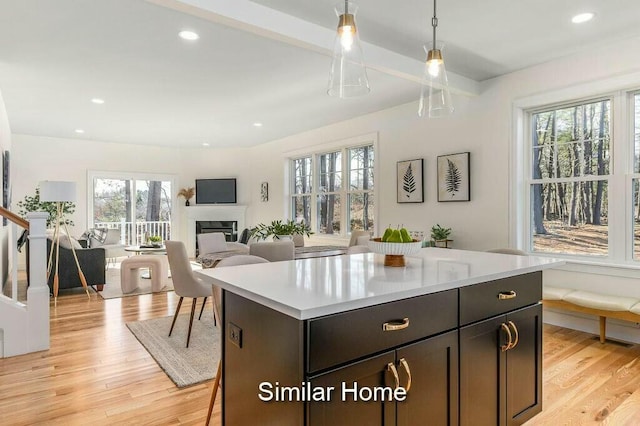 kitchen featuring a glass covered fireplace, open floor plan, light countertops, and light wood finished floors