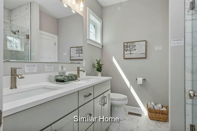 bathroom featuring a sink, toilet, marble finish floor, and a shower stall