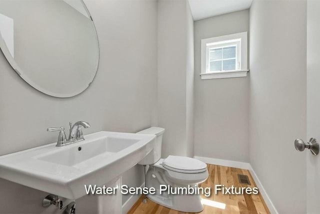 bathroom featuring wood finished floors, visible vents, baseboards, a sink, and toilet