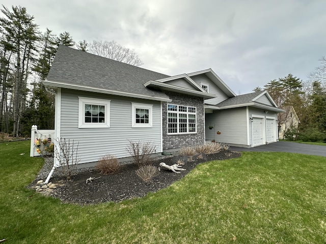 ranch-style house with an attached garage, a shingled roof, a front yard, and aphalt driveway