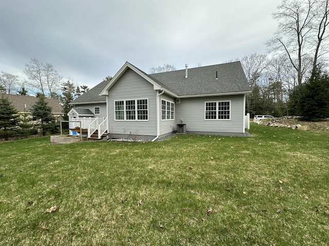 back of house featuring a lawn, a shingled roof, and a deck