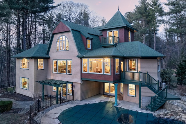 8 Spruce Point Rd, Kittery, ME 03904 - back of house at dusk with a gambrel roof, stairs, a patio area, a balcony, and a shingled roof