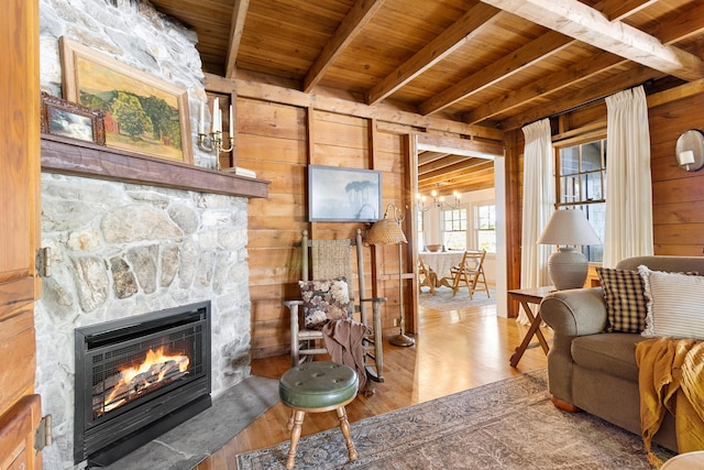 living room with wooden walls, a fireplace, wooden ceiling, wood finished floors, and beamed ceiling