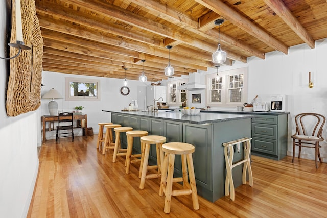 kitchen featuring a breakfast bar area, dark countertops, wood ceiling, and light wood-style floors