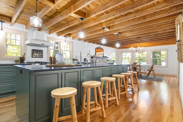 kitchen with dark countertops, light wood-style floors, a wealth of natural light, beamed ceiling, and wood ceiling