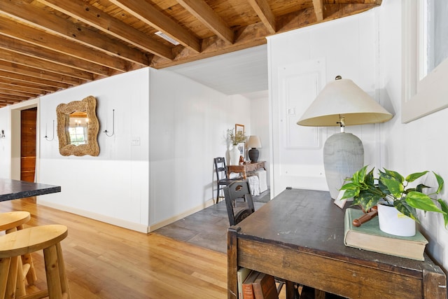 dining space with beamed ceiling, wooden ceiling, baseboards, and wood finished floors