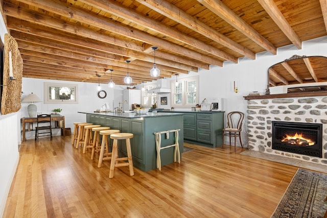 kitchen with dark countertops, light wood-style floors, custom range hood, a fireplace with flush hearth, and green cabinets