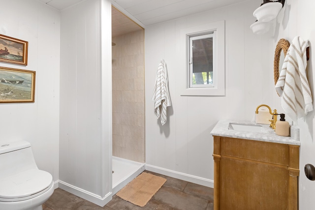 bathroom with toilet, baseboards, a shower stall, and vanity
