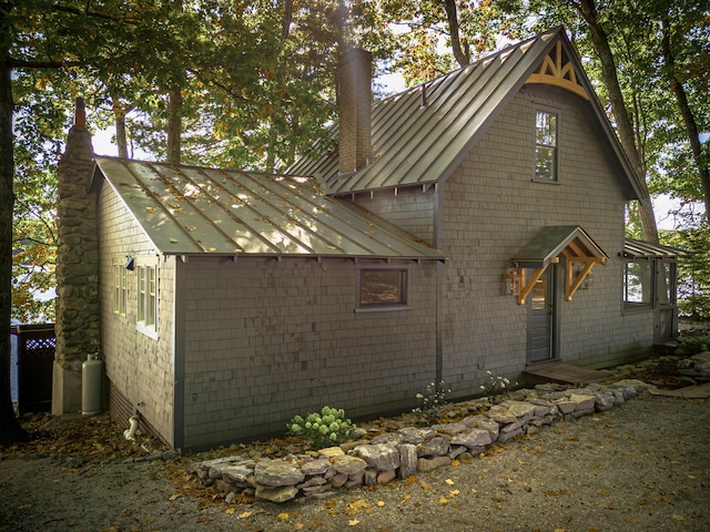exterior space featuring metal roof, a chimney, and a standing seam roof