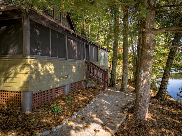 view of side of property with a water view, a sunroom, and crawl space