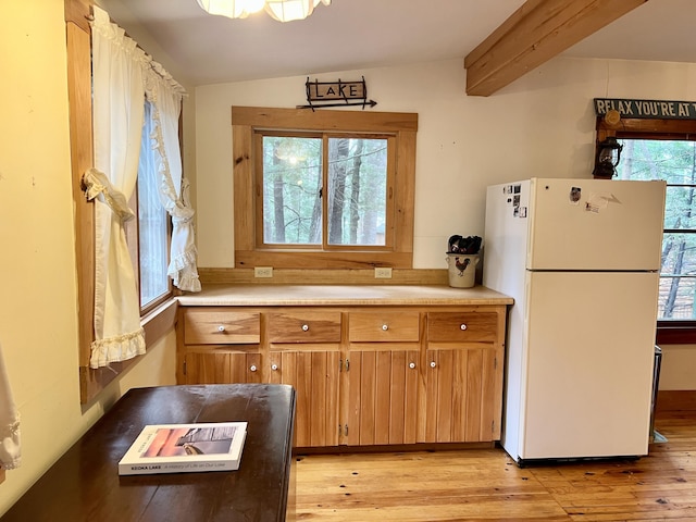 kitchen with light wood-style floors, brown cabinets, light countertops, and freestanding refrigerator
