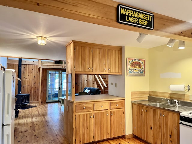 kitchen featuring white appliances, a sink, light wood-type flooring, a wood stove, and french doors