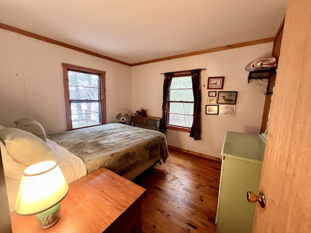 bedroom featuring hardwood / wood-style floors, baseboards, and crown molding