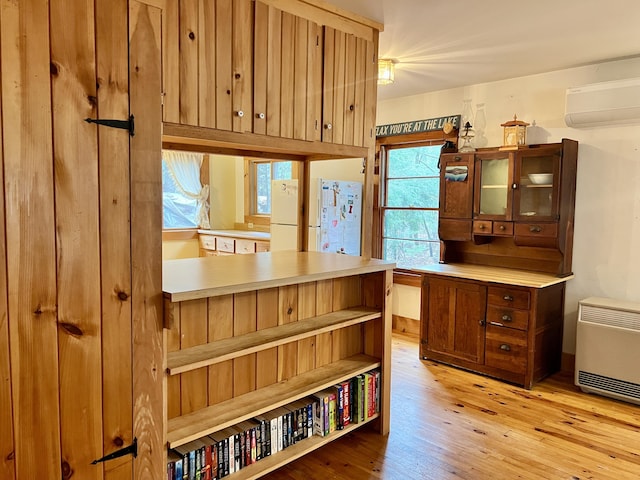 interior space featuring heating unit, light wood-style flooring, and a wall mounted AC