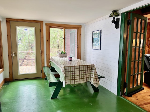 dining space with wood finished floors and wooden walls