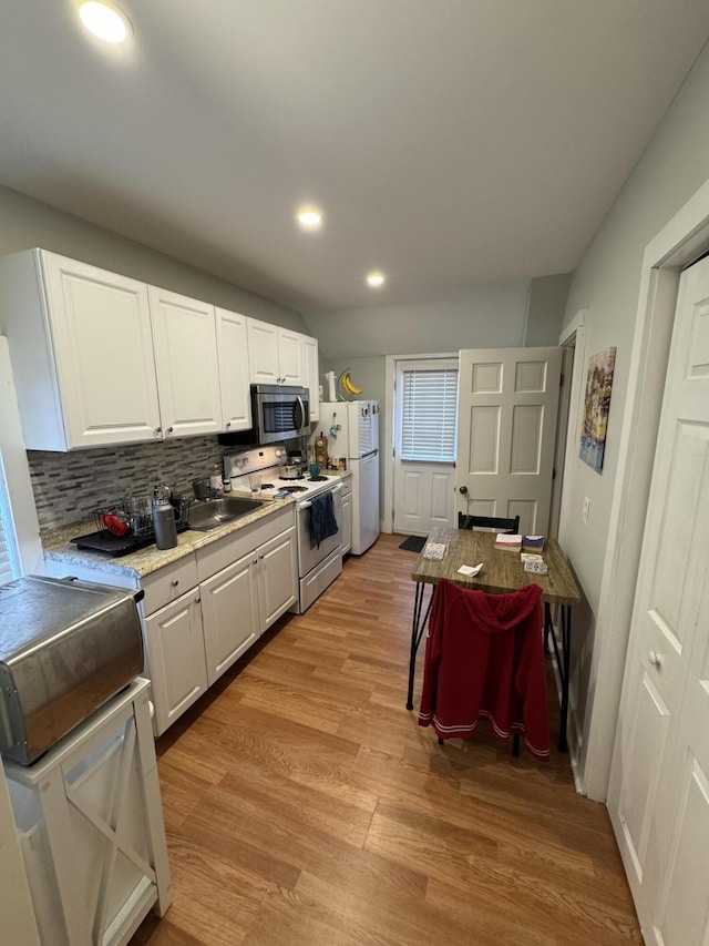 64 Gray St, Portland, ME 04102 - kitchen with white appliances, white cabinetry, light wood-style flooring, decorative backsplash, and recessed lighting