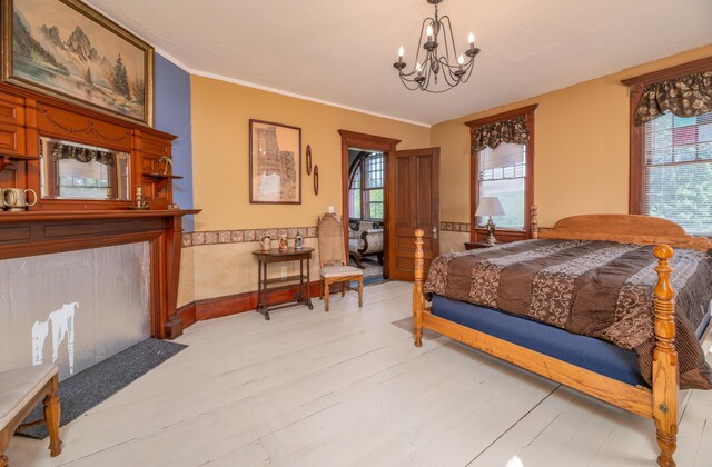1135 E Pittston Rd, Pittston, ME 04345 - bedroom with light wood-style floors, a notable chandelier, ornamental molding, and wainscoting