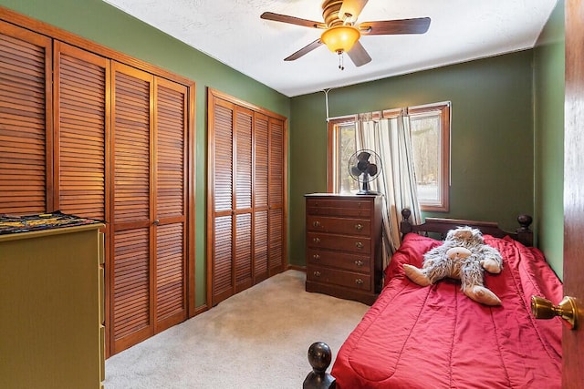 carpeted bedroom featuring two closets and ceiling fan