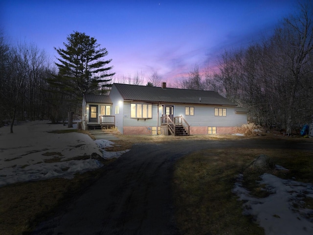 back of property featuring metal roof, driveway, and a chimney