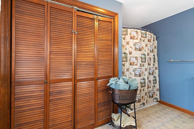 bathroom with curtained shower, baseboards, and a closet