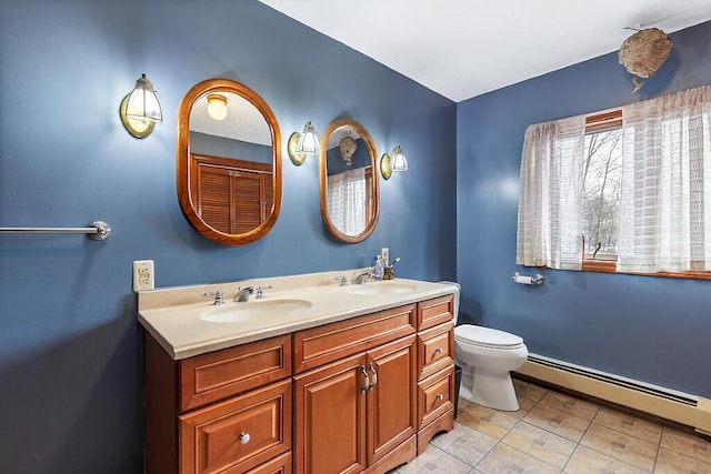 bathroom with a sink, baseboard heating, double vanity, and toilet