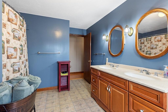 bathroom with double vanity, baseboards, and a sink