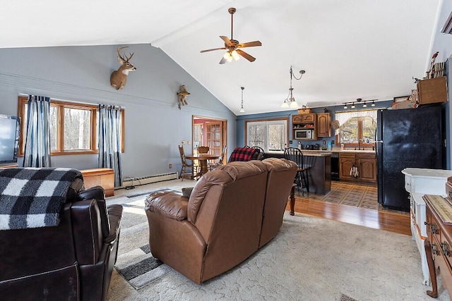 living room with a wealth of natural light, a baseboard radiator, light wood-type flooring, and a ceiling fan