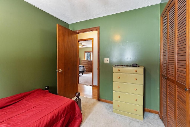 carpeted bedroom with a closet, baseboards, and a textured ceiling
