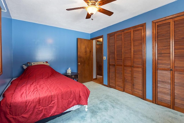 carpeted bedroom with two closets and ceiling fan