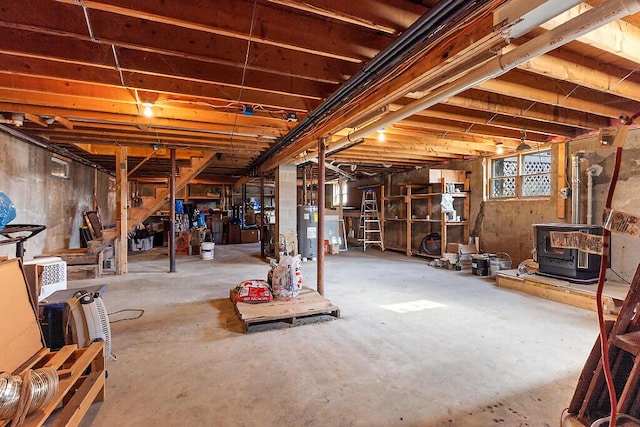 basement featuring a wood stove, electric water heater, and stairs