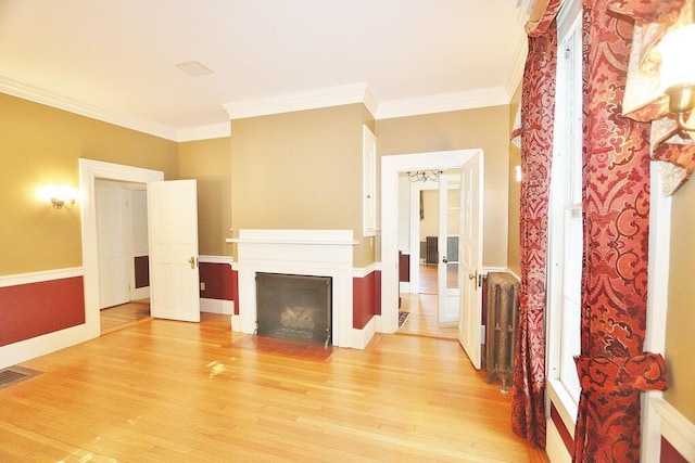 living area featuring visible vents, a fireplace with flush hearth, light wood-style flooring, and crown molding