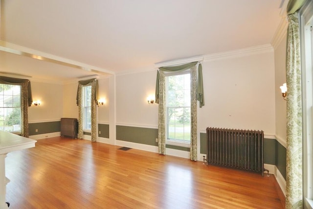 spare room with radiator, wood finished floors, and ornamental molding