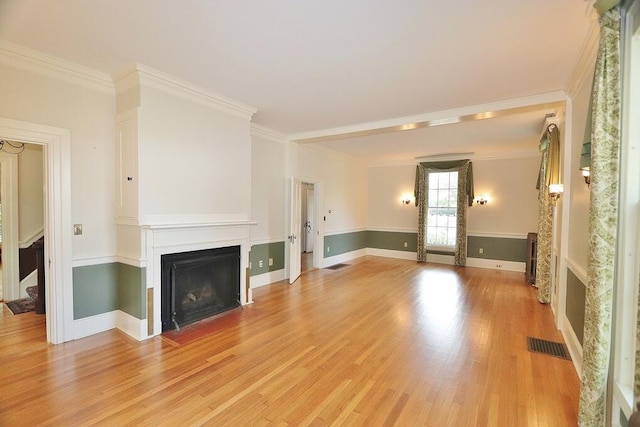 unfurnished living room featuring a fireplace with flush hearth, light wood-style floors, visible vents, and ornamental molding