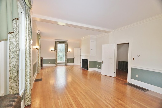 unfurnished living room featuring visible vents, a fireplace, wainscoting, crown molding, and light wood-type flooring