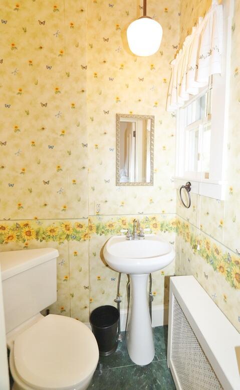 half bath featuring tile patterned floors, wallpapered walls, and toilet