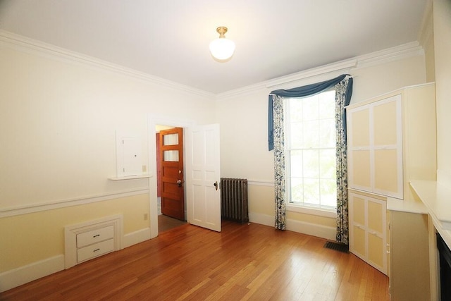 unfurnished bedroom with radiator, wood finished floors, baseboards, and ornamental molding