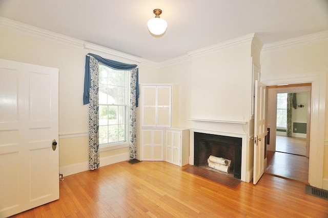 unfurnished living room with a fireplace with flush hearth, light wood-style flooring, crown molding, and visible vents