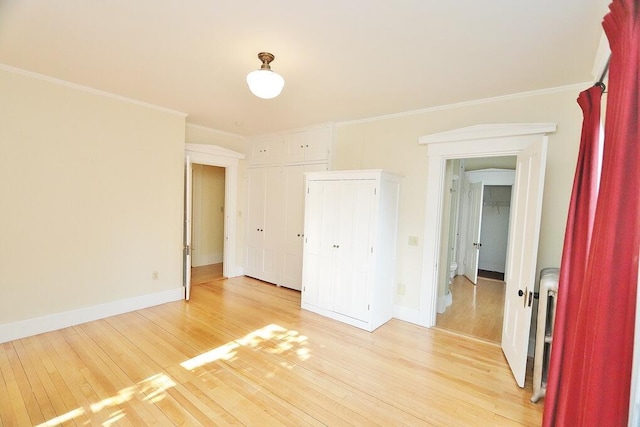 unfurnished bedroom featuring light wood-type flooring, baseboards, and crown molding