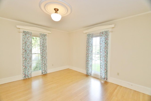 empty room with crown molding, wood finished floors, and baseboards