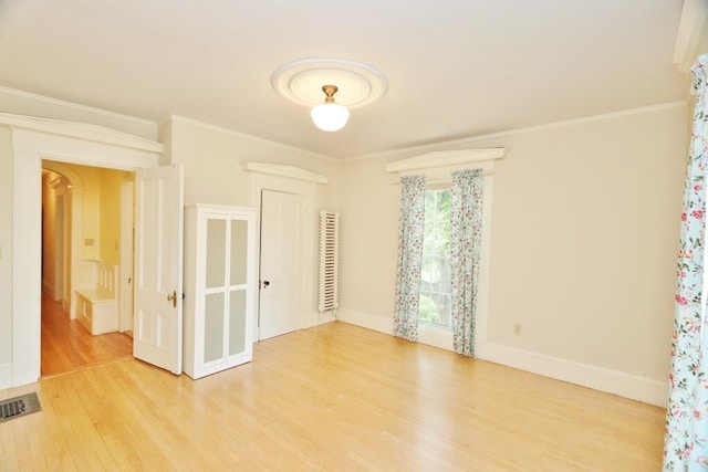 unfurnished room with visible vents, baseboards, wood finished floors, and ornamental molding