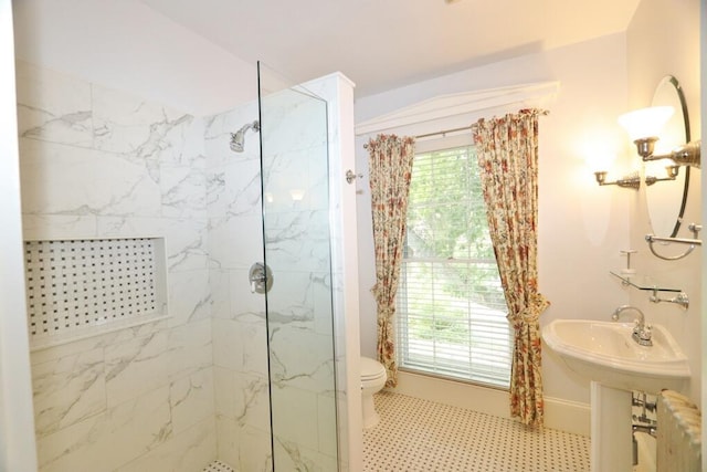 full bath with a marble finish shower, baseboards, and toilet