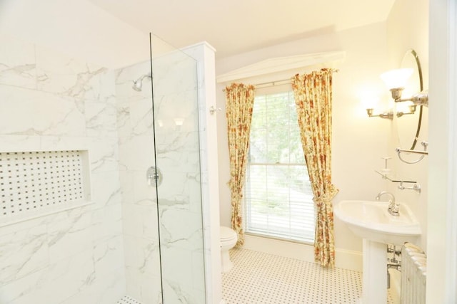 full bath featuring radiator, baseboards, a marble finish shower, a sink, and toilet