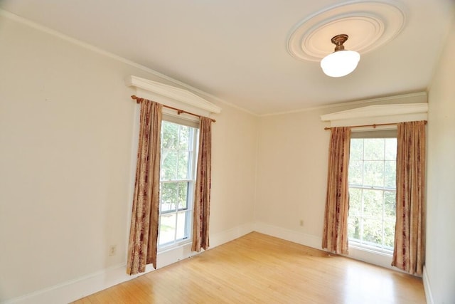 unfurnished room with baseboards, light wood-type flooring, a wealth of natural light, and ornamental molding