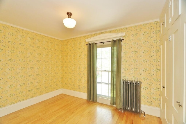empty room with wallpapered walls, radiator, baseboards, and light wood-type flooring
