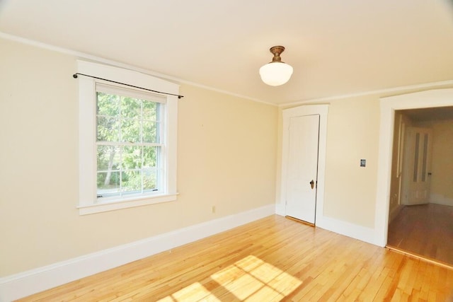 unfurnished room featuring baseboards, light wood-style floors, and crown molding