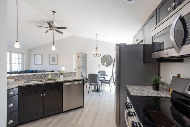 kitchen featuring vaulted ceiling, a sink, ceiling fan with notable chandelier, light wood-type flooring, and appliances with stainless steel finishes